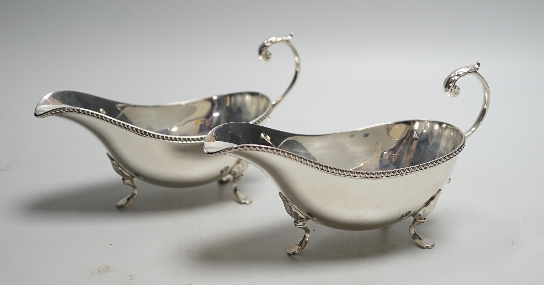 A pair of Elizabeth II silver sauce boats, with flying scroll handles, Poston Products Ltd, Birmingham, 1961, length 18cm, 11.3oz.